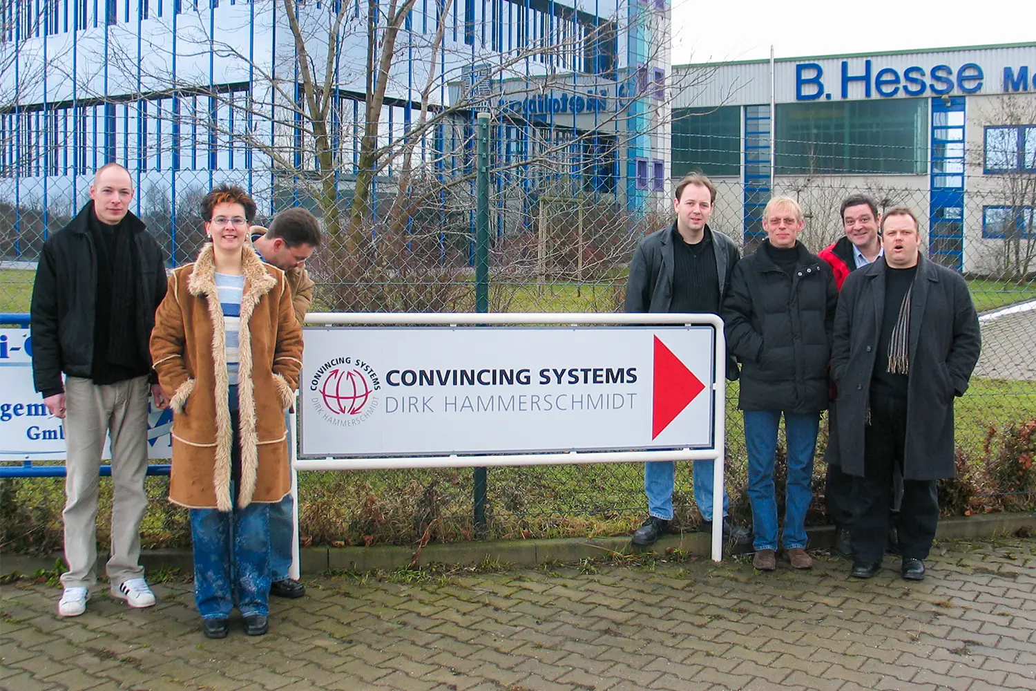 Gruppenfoto vor dem Firmenschild von Convincing Systems mit mehreren Personen im Außenbereich.