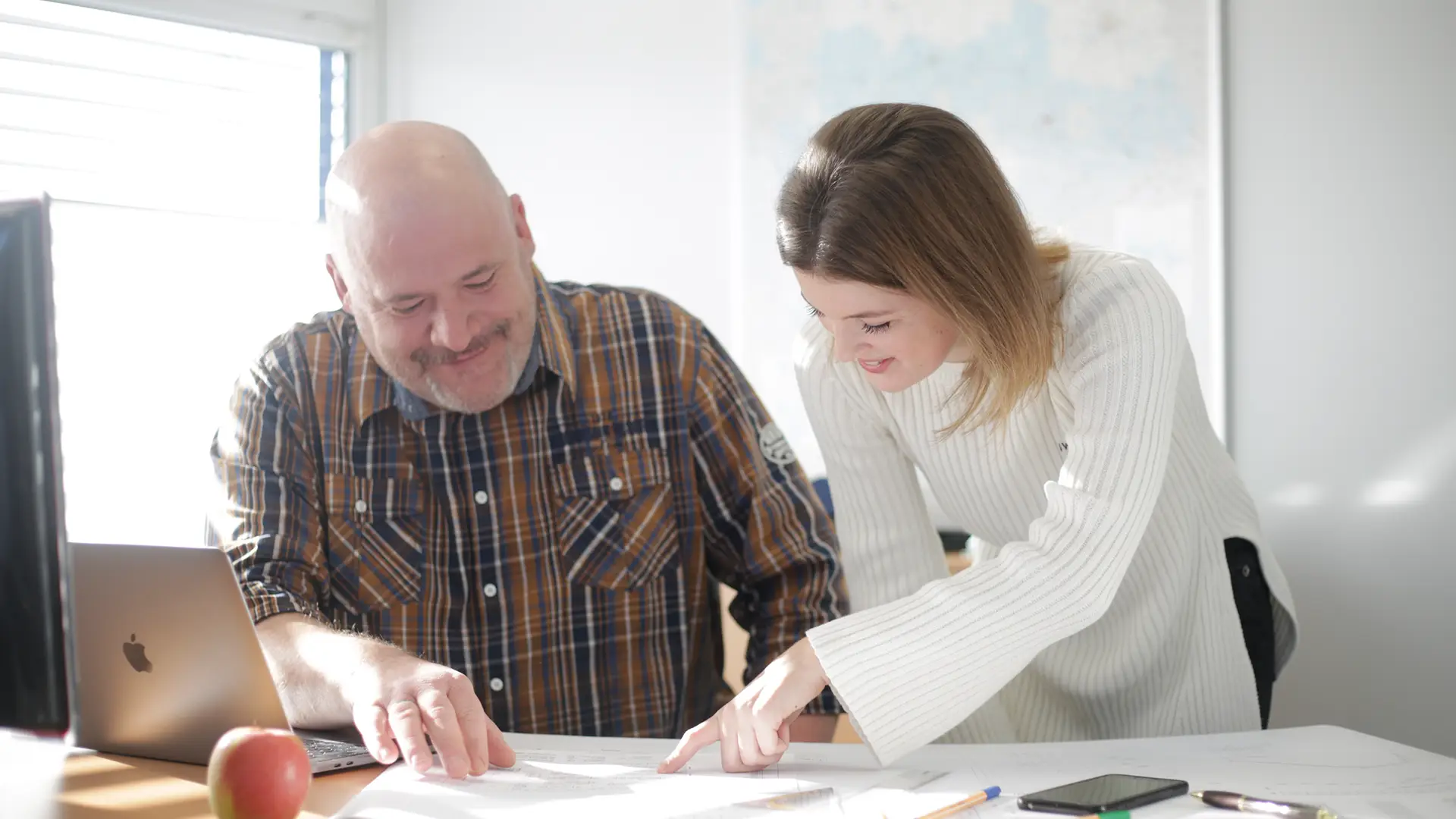 Teamarbeit im modernen Büro. Mann und Frau besprechen gemeinsam Baupläne oder Projektunterlagen. Perfekte Darstellung für Planung, Projektmanagement und Teamwork.
