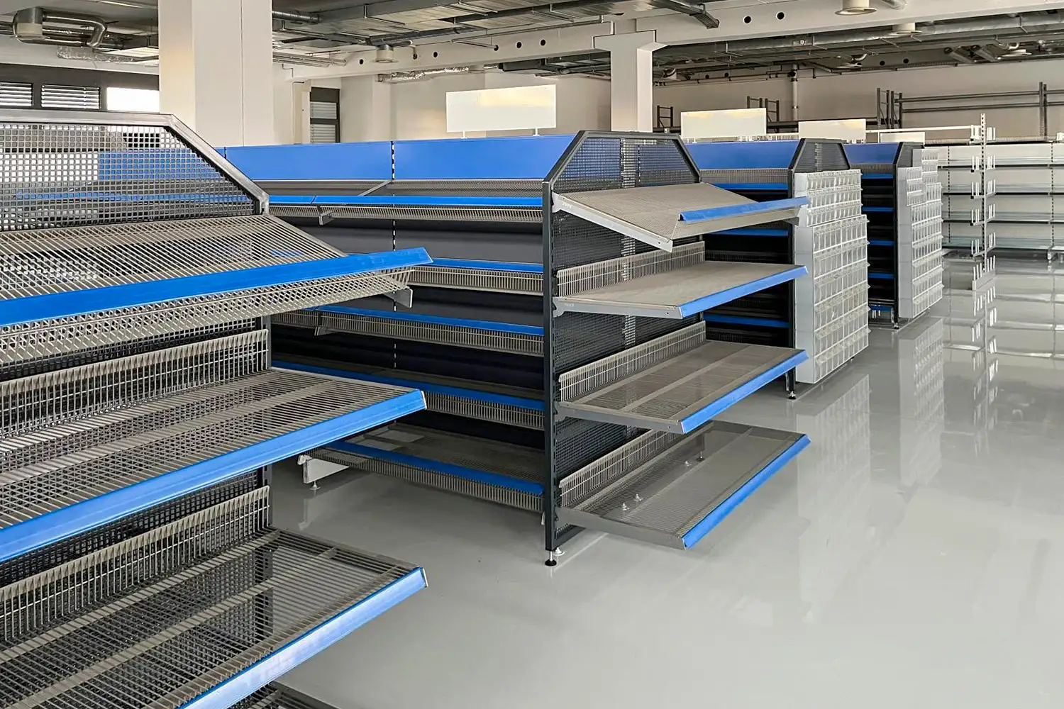 Metallregale mit blauen Akzenten in einer modernen Handelsumgebung. Optimal für die Warenpräsentation im Einzelhandel und im Non-Food-Bereich.