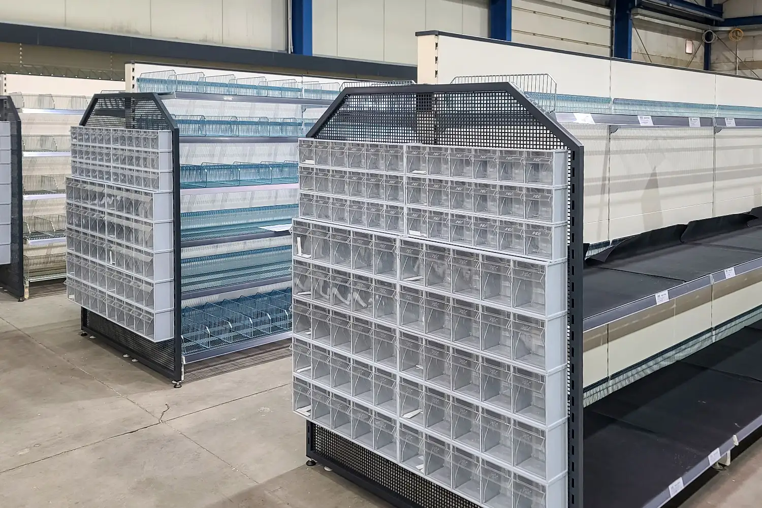 Praktische Gitterregale mit transparenten Boxen für Kleinartikel. Übersichtliche Lösung für Einzelhandel, Lager oder Baumarkt.