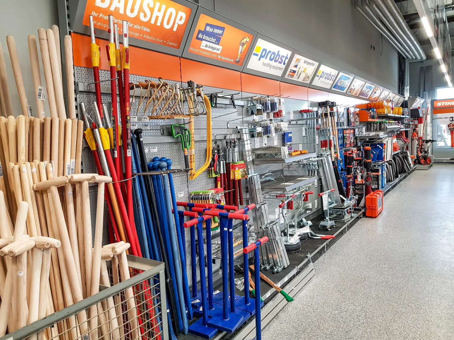 Verkaufsfläche in einem Baumarkt mit Werkzeugen, Gartengeräten und Zubehör an einer Wand mit Lochblech und Regalhaken ausgestellt.